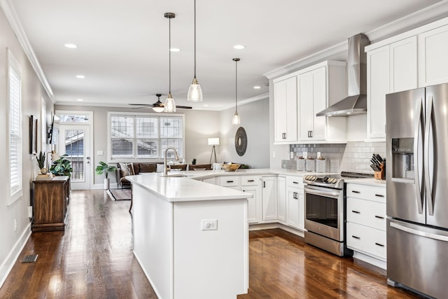 kitchen featuring sink, white cabinetry, stainless steel appliances, decorative light fixtures, and wall chimney exhaust hood