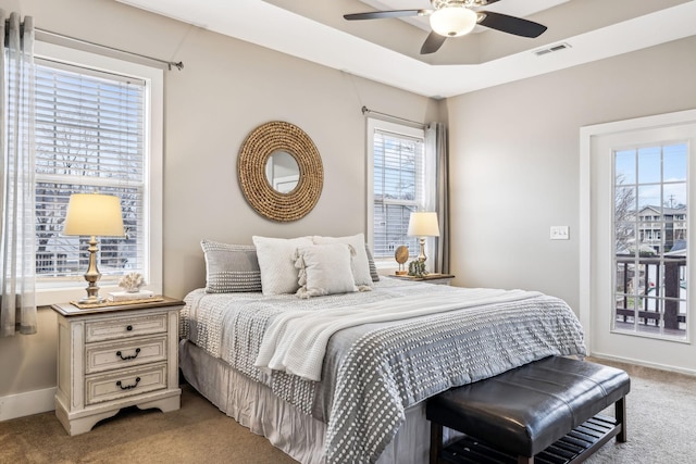 carpeted bedroom with ceiling fan and a tray ceiling