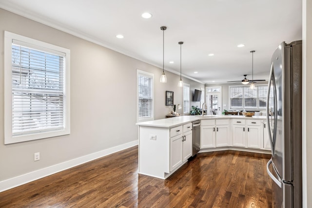 kitchen with pendant lighting, dark wood-type flooring, appliances with stainless steel finishes, white cabinetry, and kitchen peninsula