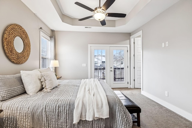 carpeted bedroom with french doors, ceiling fan, a tray ceiling, and access to exterior