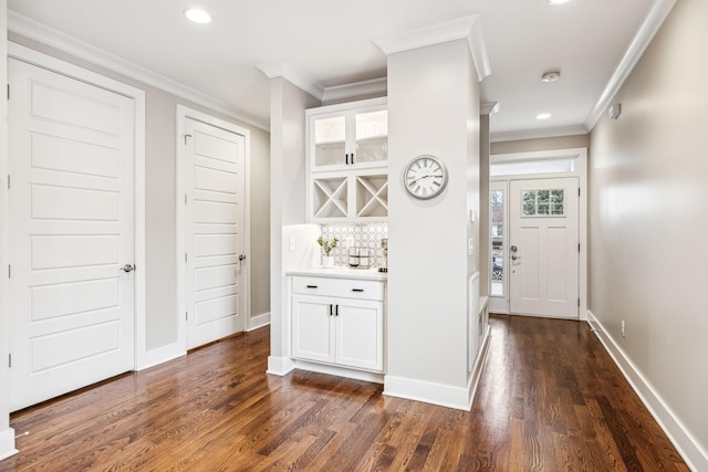 interior space with ornamental molding, white cabinets, dark hardwood / wood-style flooring, and decorative backsplash