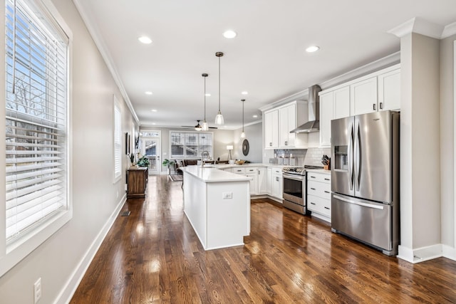 kitchen with appliances with stainless steel finishes, white cabinets, decorative light fixtures, kitchen peninsula, and wall chimney exhaust hood