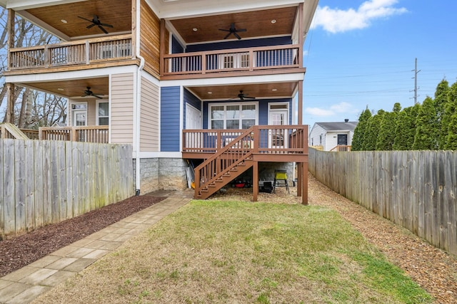 rear view of property featuring ceiling fan, a yard, and a balcony