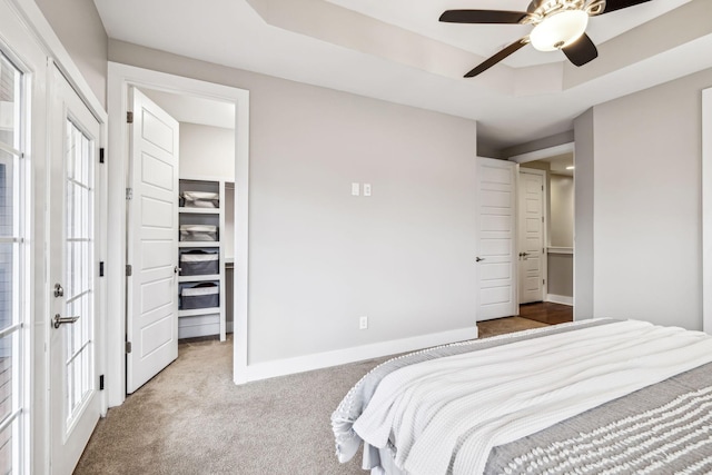 bedroom featuring french doors, a spacious closet, a raised ceiling, light carpet, and a closet