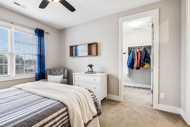 bedroom featuring ceiling fan, a closet, a spacious closet, and light carpet