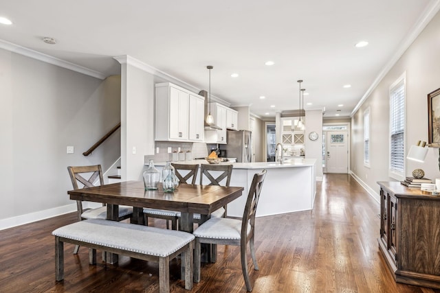 dining area featuring sink, crown molding, and dark wood-type flooring