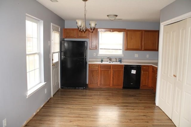 kitchen with pendant lighting, a notable chandelier, light hardwood / wood-style flooring, and black appliances