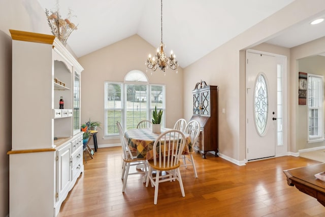 dining area featuring lofted ceiling, light hardwood / wood-style floors, and a notable chandelier