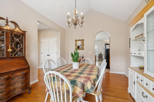 dining space with vaulted ceiling, a chandelier, and light hardwood / wood-style floors