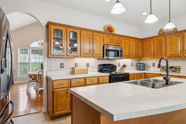 kitchen featuring sink, hanging light fixtures, appliances with stainless steel finishes, a kitchen island with sink, and decorative backsplash