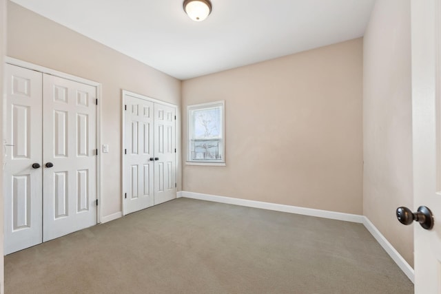 unfurnished bedroom featuring carpet flooring and two closets