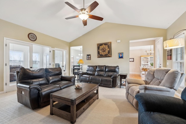 carpeted living room with ceiling fan with notable chandelier, vaulted ceiling, and a wealth of natural light