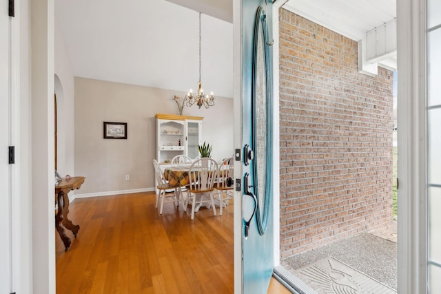 interior space featuring hardwood / wood-style flooring, brick wall, and a chandelier