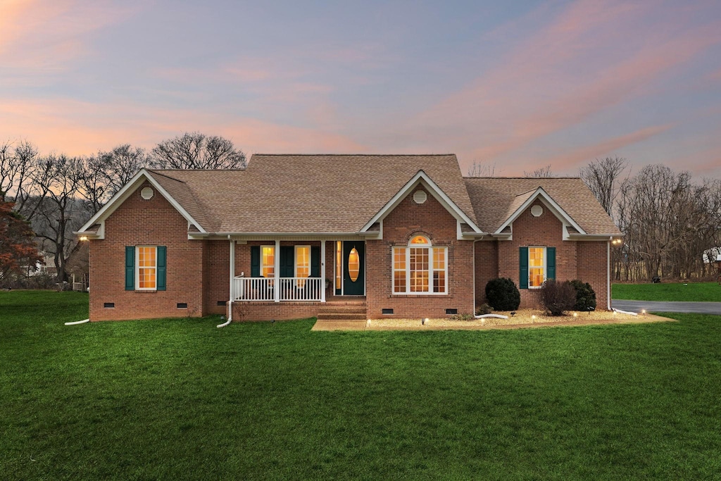 single story home with covered porch and a lawn