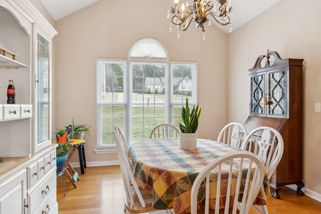 dining space with lofted ceiling, an inviting chandelier, and light wood-type flooring