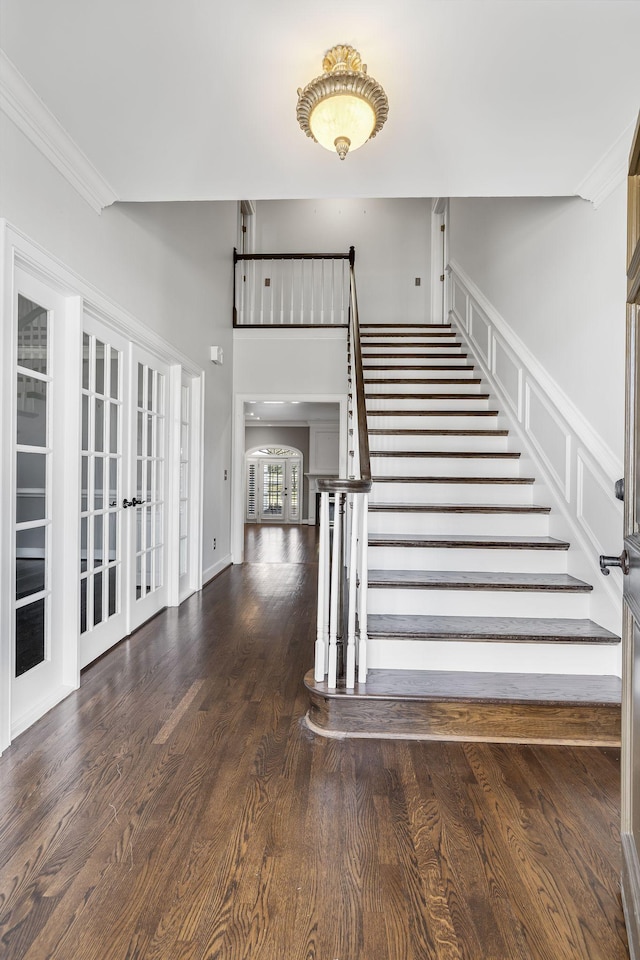 stairway featuring french doors, wood-type flooring, and crown molding