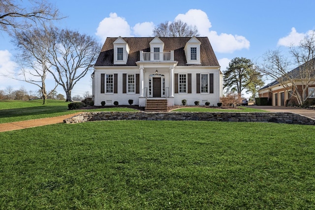 cape cod-style house featuring a balcony and a front lawn