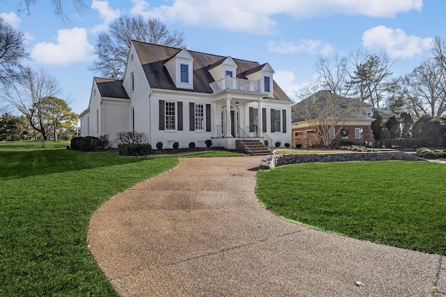 cape cod home featuring a front lawn and a balcony