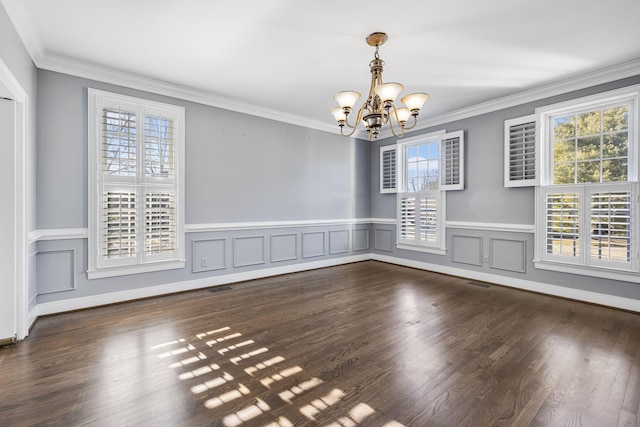 unfurnished room featuring an inviting chandelier, ornamental molding, and dark hardwood / wood-style flooring