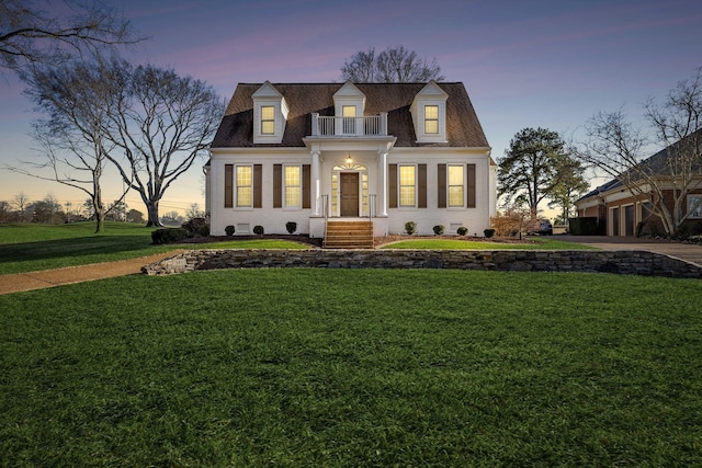 cape cod house featuring a balcony and a lawn