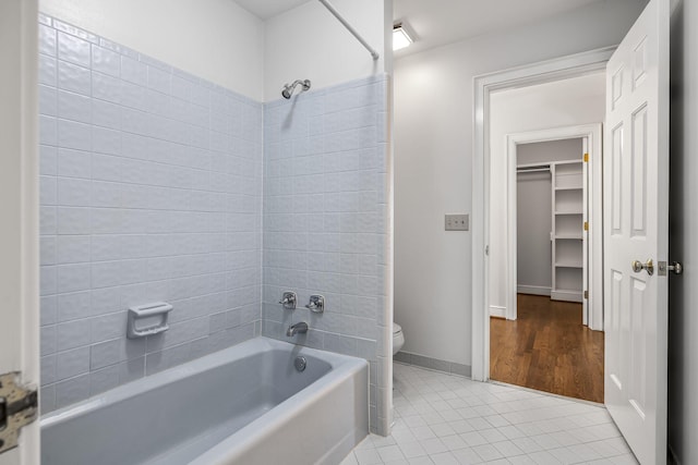 bathroom featuring tile patterned flooring, toilet, and tiled shower / bath