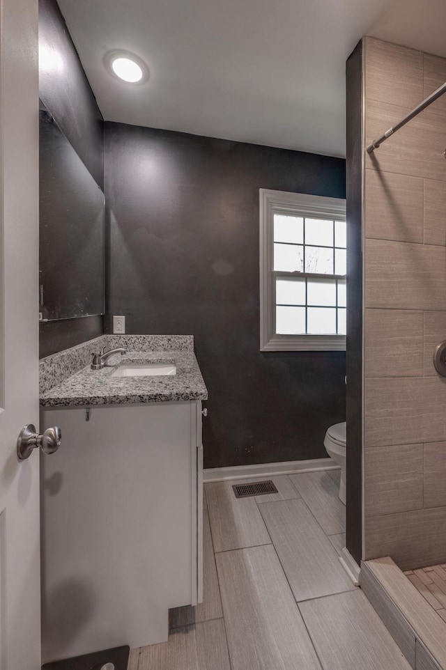 bathroom with vanity, toilet, and a tile shower