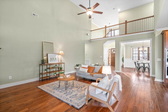 living room with hardwood / wood-style flooring, a towering ceiling, and ceiling fan with notable chandelier