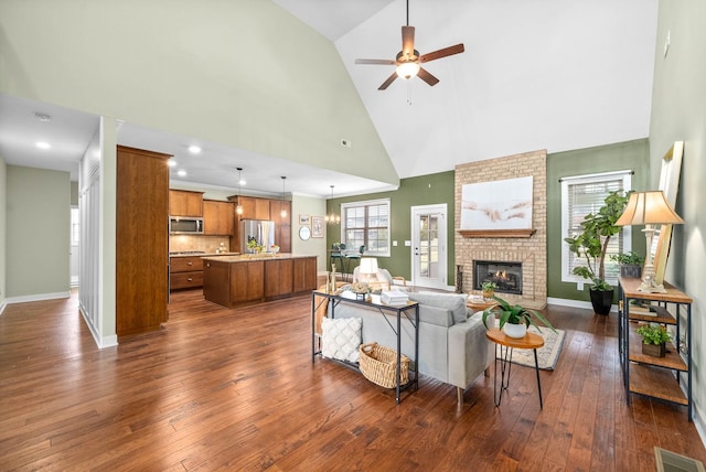 living room with a brick fireplace, dark wood-type flooring, high vaulted ceiling, and ceiling fan