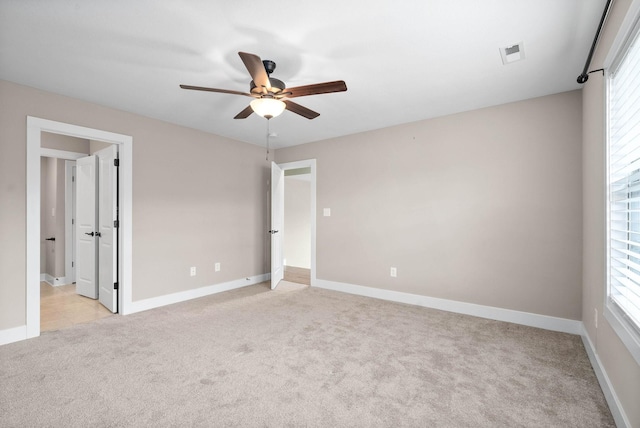 unfurnished bedroom with multiple windows, light carpet, and ceiling fan