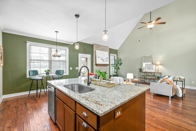 kitchen featuring pendant lighting, sink, dark wood-type flooring, a kitchen island with sink, and light stone counters