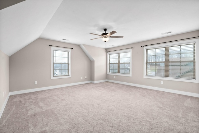 additional living space featuring ceiling fan, a healthy amount of sunlight, vaulted ceiling, and light carpet