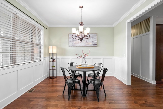 dining room with crown molding, dark wood-type flooring, and an inviting chandelier