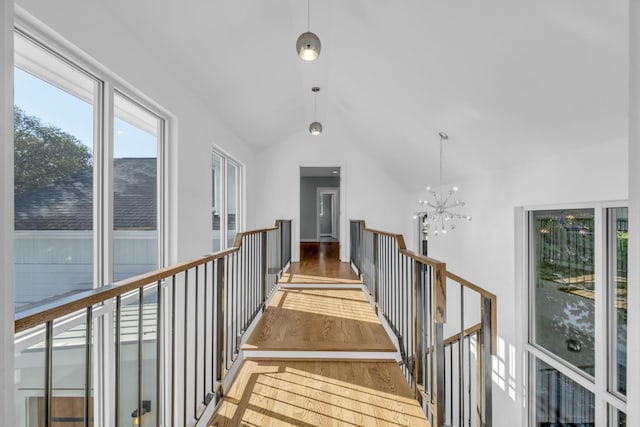 hall with lofted ceiling, a notable chandelier, and wood-type flooring