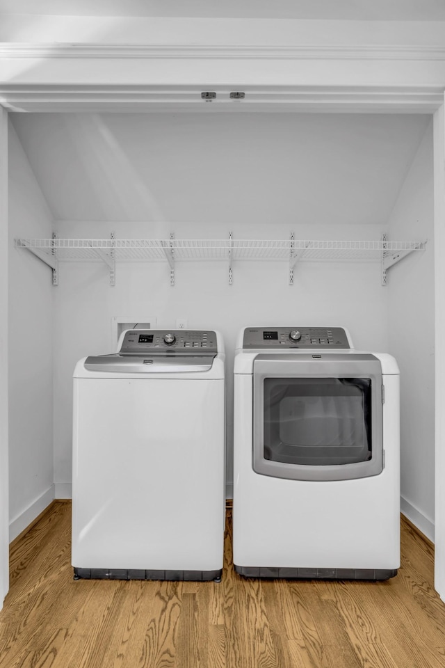 laundry room with independent washer and dryer and light hardwood / wood-style flooring