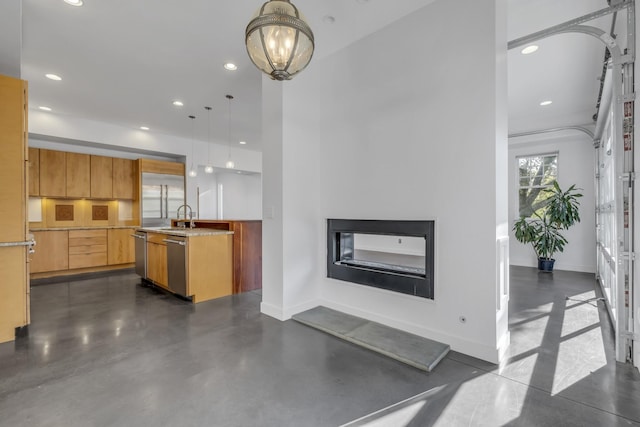 interior space featuring pendant lighting, dishwasher, sink, and a center island with sink