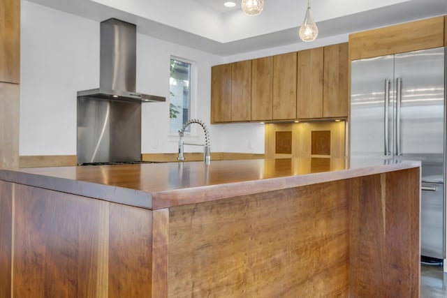 kitchen featuring stainless steel appliances, sink, hanging light fixtures, and wall chimney range hood