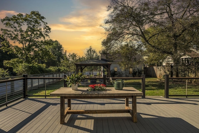 deck at dusk featuring a gazebo