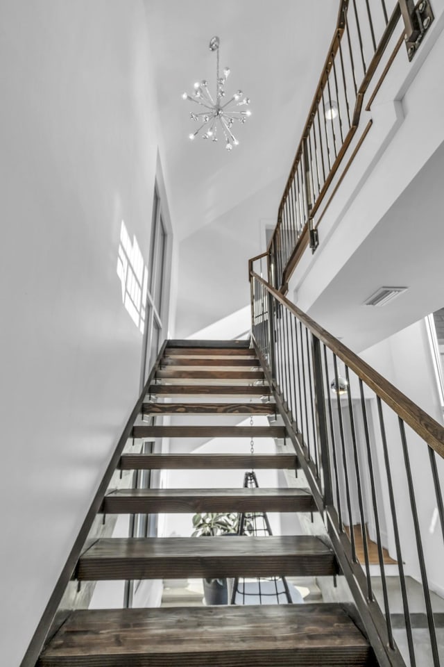 staircase featuring a towering ceiling and an inviting chandelier