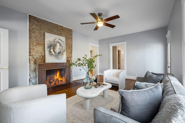 living room featuring ceiling fan, a brick fireplace, and light wood-type flooring