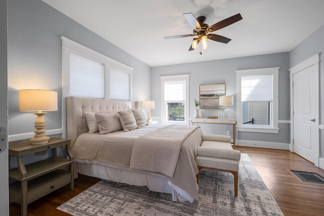 bedroom featuring multiple windows, dark hardwood / wood-style floors, and ceiling fan