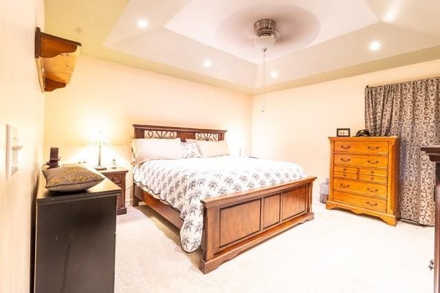 carpeted bedroom featuring a raised ceiling and ceiling fan