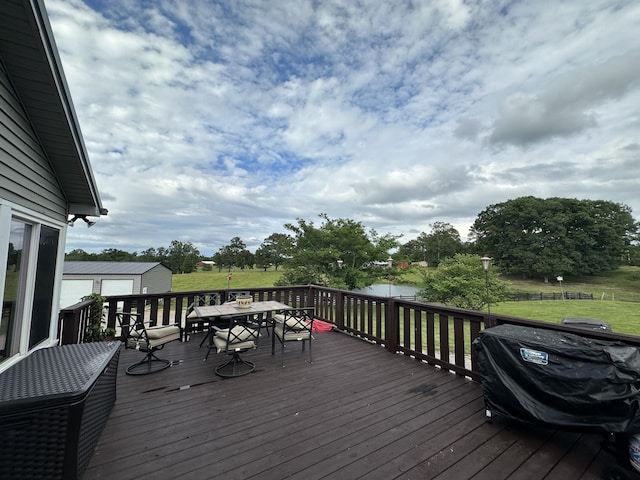 deck with a grill, a lawn, and a storage unit