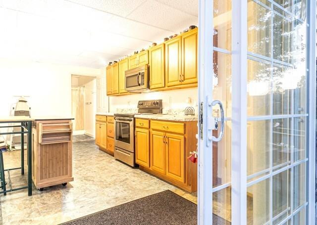 kitchen with stainless steel appliances, a breakfast bar area, and a drop ceiling