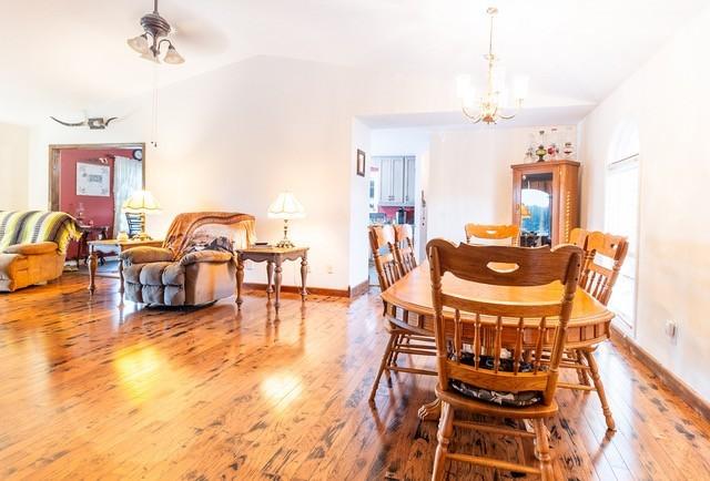 dining room with hardwood / wood-style flooring, lofted ceiling, and a notable chandelier