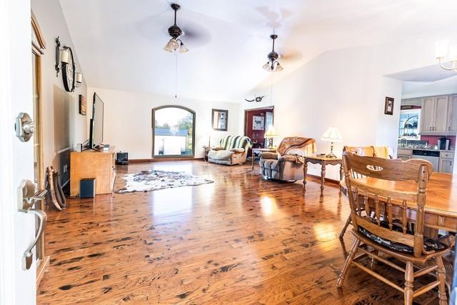 living room featuring vaulted ceiling, plenty of natural light, hardwood / wood-style floors, and ceiling fan