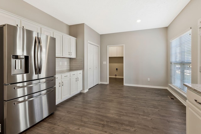 kitchen featuring white cabinetry, stainless steel refrigerator with ice dispenser, light stone countertops, and dark wood-type flooring