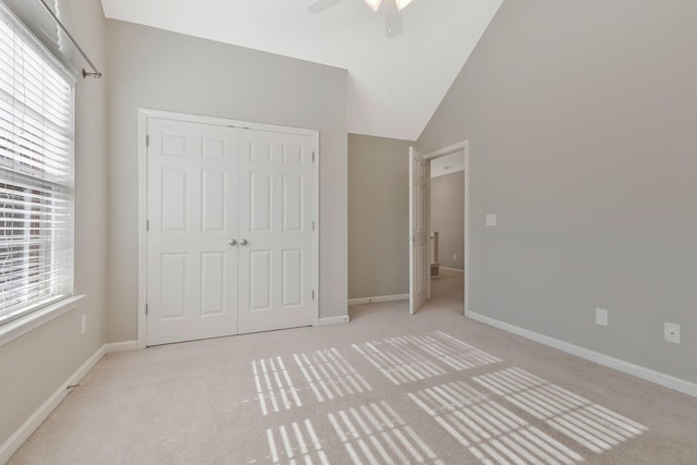 unfurnished bedroom with ceiling fan, high vaulted ceiling, light carpet, and a closet