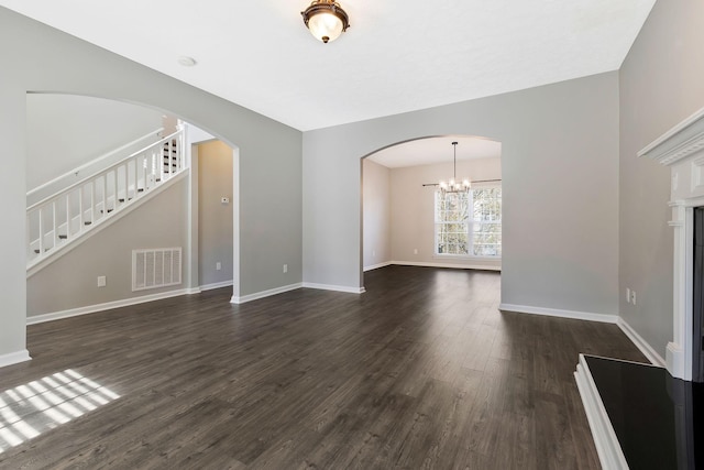 unfurnished living room with dark wood-type flooring and a chandelier