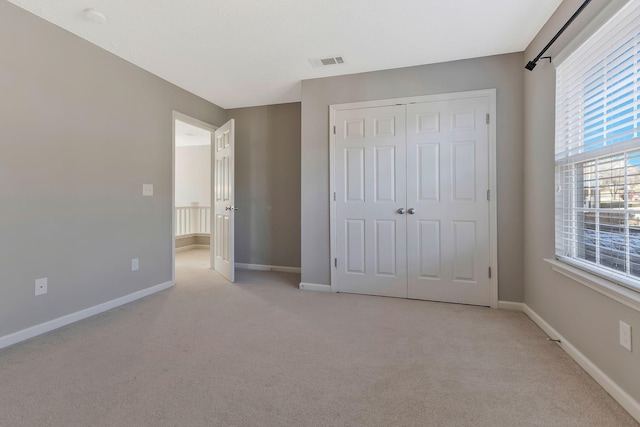 unfurnished bedroom with light colored carpet and a closet