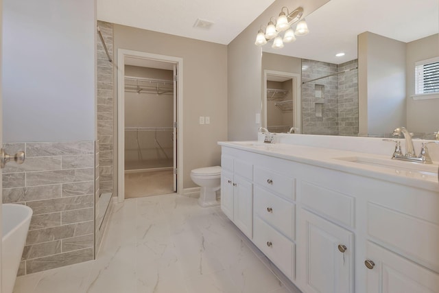 bathroom with vanity, toilet, and tiled shower